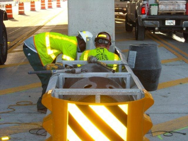 Two men performing attenuator installation for commercial fence installation in Nashville.